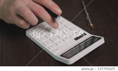 Calculator Hand Pressing Numeric Keys, Business Analyst Calculating Expenses On Dark Wood Desk With Pen And Glasses, Focused Professional Mood, Closeup Emphasizing Precision And Workflow Calculator Hand Pressing Numeric Keys, Business Analyst Calculating Expenses On Dark Wood Desk With Pen And Glasses, Focused Professional Mood, Closeup Emphasizing Precision And Workflow 137745025
