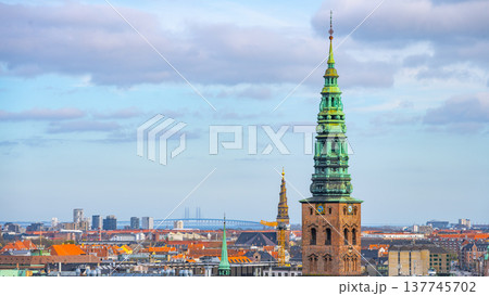 Visitors explore Nikolaj Kunsthal, a contemporary arts center located in the former St. Nicholas Church in Copenhagen, Denmark. The area features historic architecture and vibrant city views. 137745702