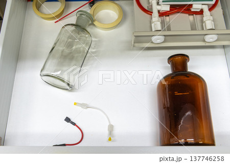 glass bottles, laboratory equipment, tubes in white drawer. glass bottles, laboratory equipment, tubes in white drawer. 137746258