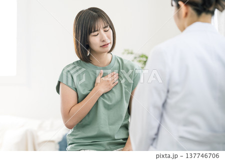 体調が悪く病院で医師の診察を受ける若い女性 137746706