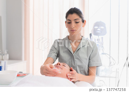 Cosmetologist facial treatment on woman lying in 137747258