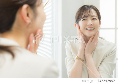 鏡を見てメイクする女性  137747957