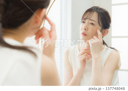 鏡を見て悩む女性 137748048
