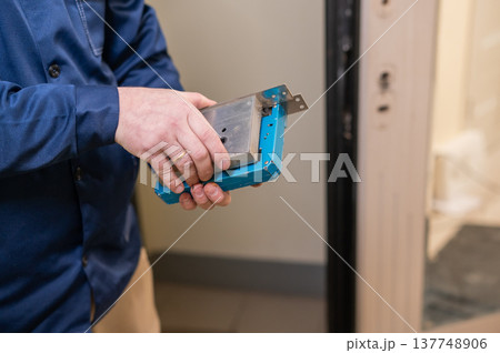 The technician installs a smart electronic lock on the front door. The technician installs a smart electronic lock on the front door. 137748906
