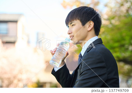 公園でペットボトルの水を飲みリフレッシュする新人ビジネスマン 上半身 横顔 137749709