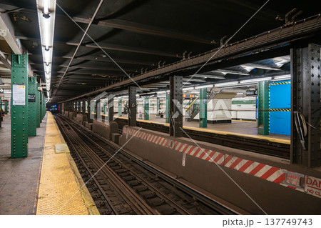Wide perspective of New York City subway tracks and platform at West 4 Street Washington Square station in Manhattan. Underground transportation infrastructure with steel beams, yellow safety edge 137749743