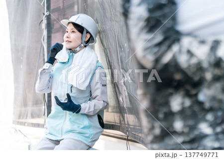 建設現場の熱中症対策。空調服を着用して水分補給をしながら休憩する女性塗装工 137749771