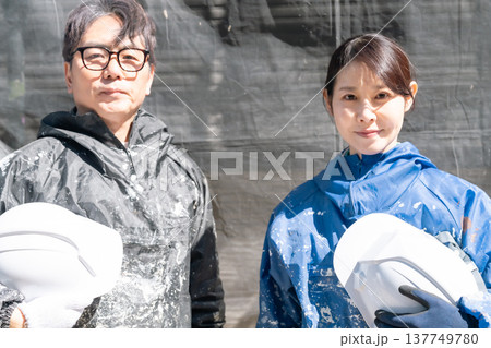 信頼の技術。外壁塗装の現場で共に働くベテランと若手の男女職人 137749780
