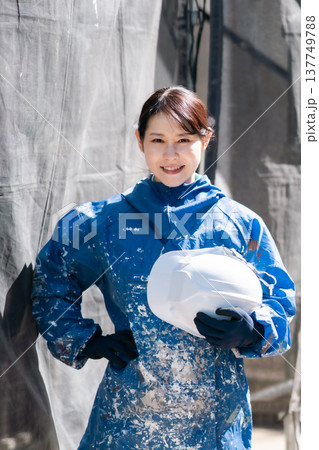 建設業界で活躍する女性職人。ペンキの付いた作業着で微笑む女性塗装工 137749788