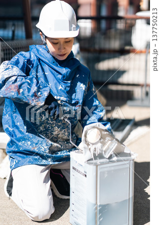 強い日差しの下準備をする女性塗装工 137750213