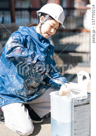 強い日差しの下準備をする女性塗装工 137750214