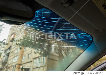 Interior shot of a damaged glass windshield with blue tint and multiple impact cracks Interior shot of a damaged glass windshield with blue tint and multiple impact cracks 137750443