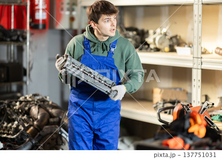Man with a car part in the workshop Man with a car part in the workshop 137751031