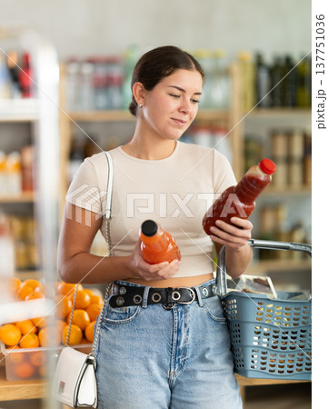 Girl hold packages bottles and choose consider juice in store 137751036
