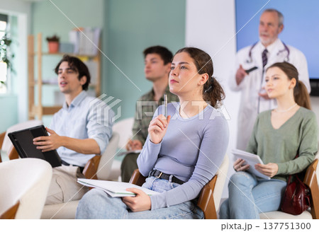 Young female student listening to lecture with medical professor in background Young female student listening to lecture with medical professor in background 137751300