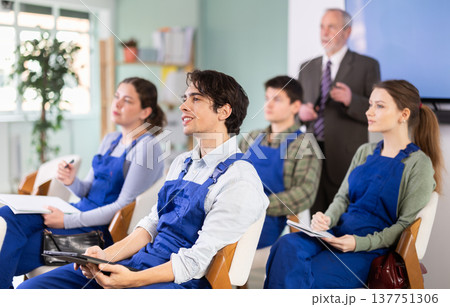 Young male student worker listening to lecture with teacher in background 137751306