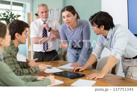 Students solving problems at table with teacher in background Students solving problems at table with teacher in background 137751345