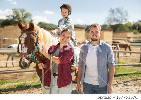 Man and woman leading horse with boy on horseback 137751676