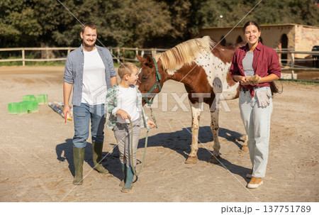 Father, mother and son riding horse together at small horse farm 137751789