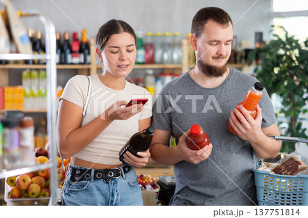 European spouses customer at shop scans QR code on juice bottle using phone camera 137751814