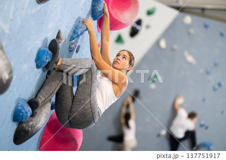 Sportive woman climbing on artificial rock wall in rock climbing gym 137751917