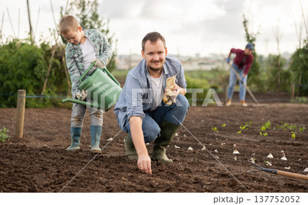 Man planting seeds boy watering beds Man planting seeds boy watering beds 137752052