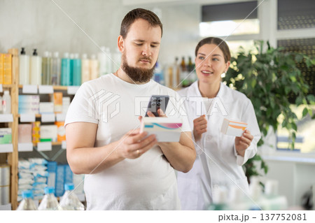 Man scans QR code on box pills label. Female pharmacist offers to choose right shampoo Man scans QR code on box pills label. Female pharmacist offers to choose right shampoo 137752081