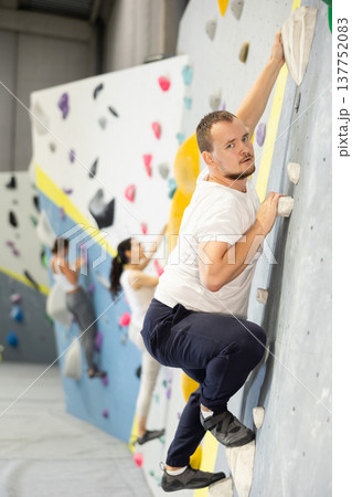Young man practicing rock climbing on climbing wall Young man practicing rock climbing on climbing wall 137752083