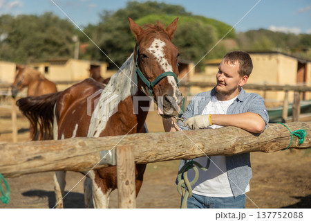 Happy man leading horse by bridle for walk in pasture Happy man leading horse by bridle for walk in pasture 137752088