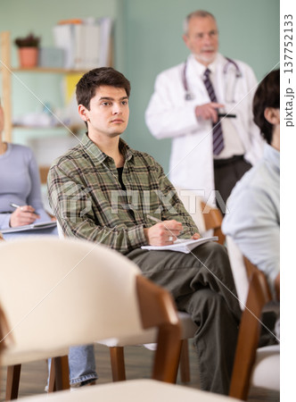 student guy listens to a lecture against the background of a doctor teacher student guy listens to a lecture against the background of a doctor teacher 137752133