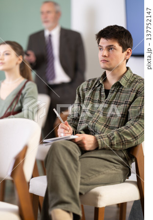 Guy student listens to a lecture, on background of the senior teacher 137752147