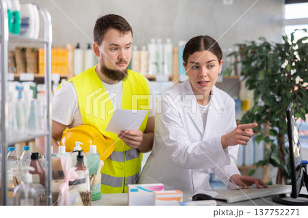 Female pharmacist consults male builder in pharmacy Female pharmacist consults male builder in pharmacy 137752271