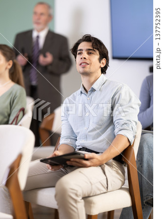 Young guy watching presentation with a teacher standing in background 137752395
