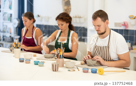 Three pottery workshop workers sculpt from raw clay Three pottery workshop workers sculpt from raw clay 137752468