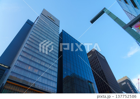 Tokyo, Japan - Oct 14 2024,  A panoramic view from below of the glass facades of skyscrapers in the Ginza district, against the backdrop of a clear blue sky, in the evening, Tokyo, Japan 137752586