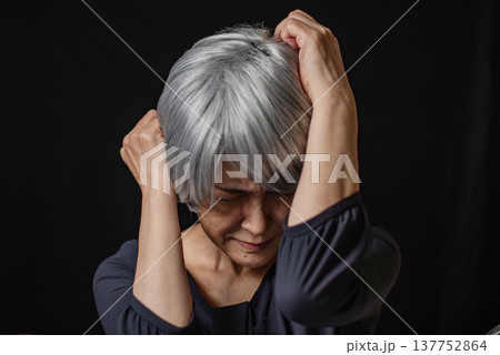 悔しそうに頭を抱える白髪のシニア女性 137752864