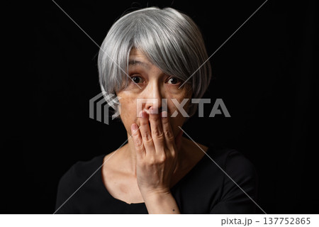 口を手で覆いビックリしている白髪のシニア女性 137752865