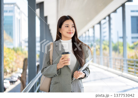 Pretty asian woman student office worker holding coffee and tablet while walking on the footbridge. Pretty asian woman student office worker holding coffee and tablet while walking on the footbridge. 137753042