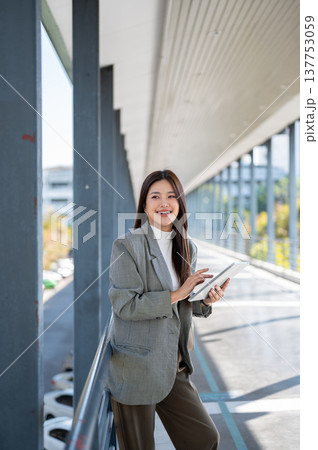 Pretty asian woman student office worker looking away from tablet standing at railing of footbridge. 137753059
