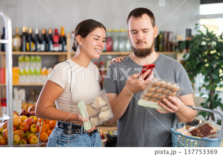 Couple purchaser scanning QR code or barcode of mushrooms in supermarket 137753369