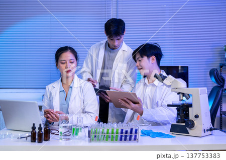 Asian scientist researcher team discussing group work over laptop and equipment at table in lab room Asian scientist researcher team discussing group work over laptop and equipment at table in lab room 137753383