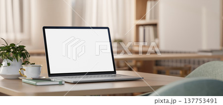 White screen laptop with book and coffee cup on wooden square table with chairs in a cosy cafe room. White screen laptop with book and coffee cup on wooden square table with chairs in a cosy cafe room. 137753491