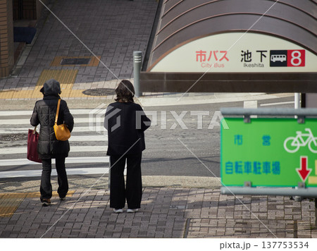名古屋市の街の市営自転車駐車場の看板の様子と横断歩道で信号待ちの通勤中の女性の姿 137753534