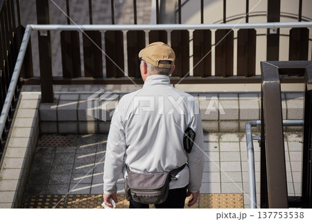 冬の朝の都市の歩道橋の階段を降りる中年男性の姿 冬の朝の都市の歩道橋の階段を降りる中年男性の姿 137753538