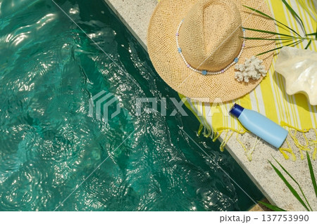 A straw hat rests on a towel beside a pool in Bali A straw hat rests on a towel beside a pool in Bali 137753990