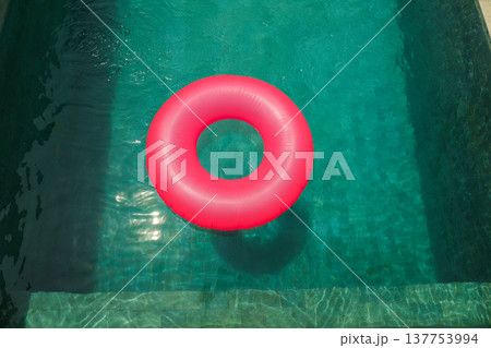 A pink float sits in a clear pool on a sunny day 137753994