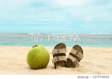 Coconut and sandals sit on the sandy beach in Bali Coconut and sandals sit on the sandy beach in Bali 137754003