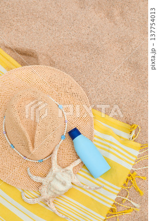 Beach towel, hat, shell, and sunscreen on the sand Beach towel, hat, shell, and sunscreen on the sand 137754013