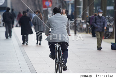 冬の昼の都市の繁華街で自転車を乗る男性サラリーマンの姿 冬の昼の都市の繁華街で自転車を乗る男性サラリーマンの姿 137754138