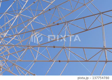 青空を背景にした観覧車の中心軸と鉄骨構造の仰角クローズアップ 青空を背景にした観覧車の中心軸と鉄骨構造の仰角クローズアップ 137754780